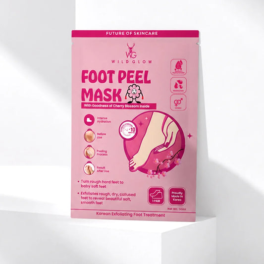 A pink stand-up pouch of Wildglow Foot Peel Mask, featuring Korean text and illustrations of a foot and cherry blossoms, displayed on a white geometric pedestal against a white background.