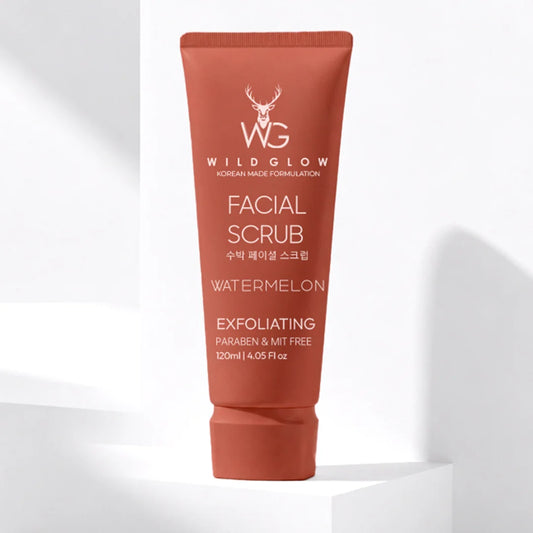 Wild Glow Watermelon Facial Scrub in a terracotta-colored squeeze tube, standing on a white geometric platform against a white background with soft shadows.
