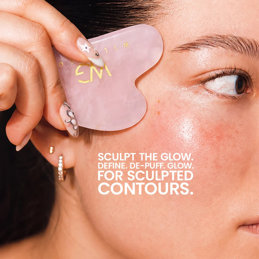 A close-up of a woman's face with a hand holding a translucent pink jade Gua sha massage tool against her cheek. White text on the image reads: 'SCULPT THE GLOW.